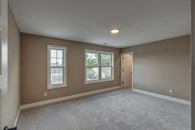 carpeted empty room featuring baseboards