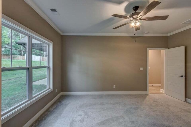 carpeted spare room featuring ceiling fan, ornamental molding, visible vents, and baseboards