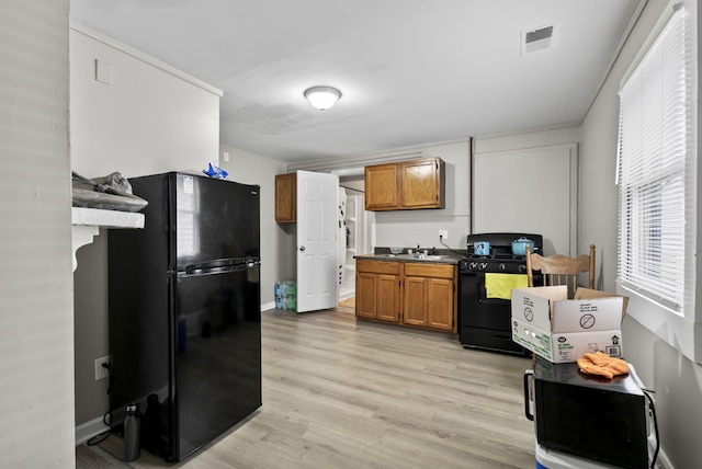 kitchen featuring black appliances, visible vents, brown cabinets, and a sink