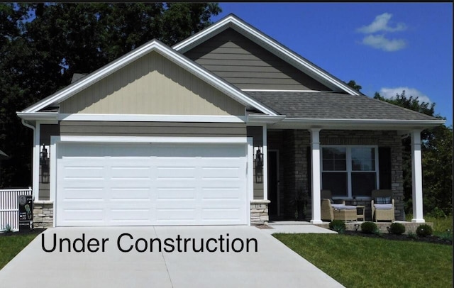 view of front of home featuring an attached garage, covered porch, a shingled roof, stone siding, and driveway