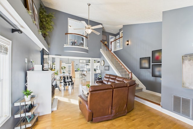 living area with visible vents, stairway, light wood-type flooring, and a ceiling fan