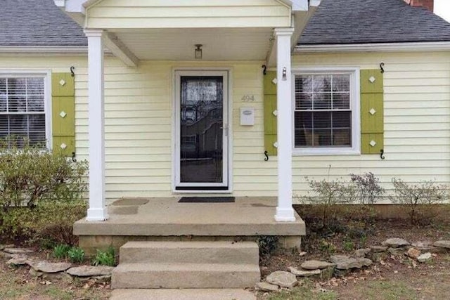 doorway to property featuring a shingled roof