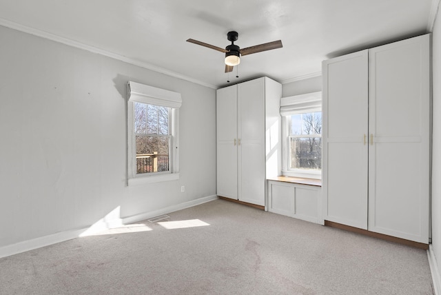 unfurnished bedroom with ornamental molding, multiple windows, baseboards, and light carpet