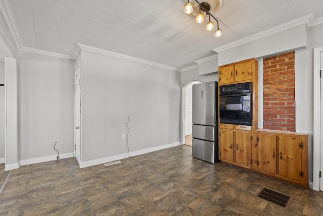 kitchen with visible vents, ornamental molding, black oven, freestanding refrigerator, and arched walkways