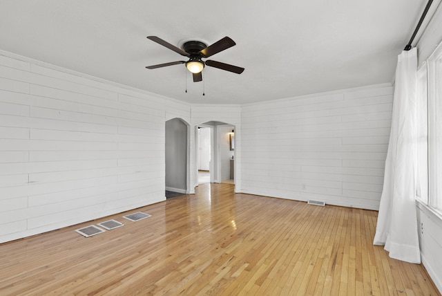 spare room with arched walkways, visible vents, light wood finished floors, and a ceiling fan