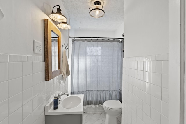 bathroom with tile walls, a textured ceiling, marble finish floor, and toilet