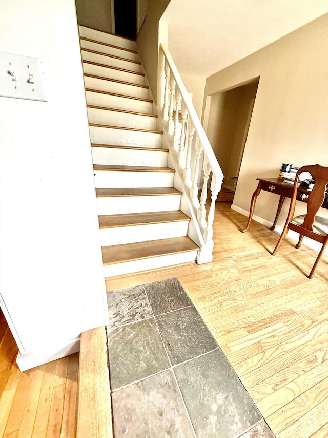 staircase featuring baseboards and wood finished floors