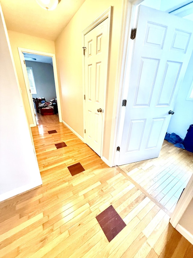 corridor with baseboards and light wood finished floors