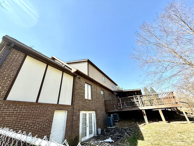 view of side of property featuring central AC unit, a deck, french doors, and brick siding