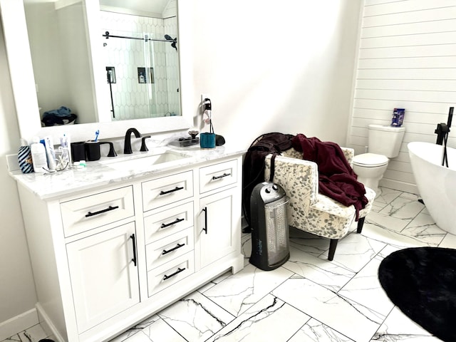 bathroom featuring marble finish floor, a freestanding bath, toilet, a stall shower, and vanity