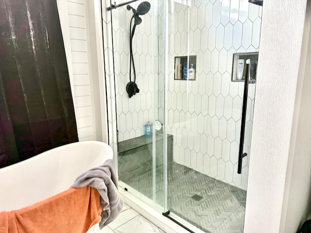 full bath with a freestanding tub, a shower stall, and marble finish floor