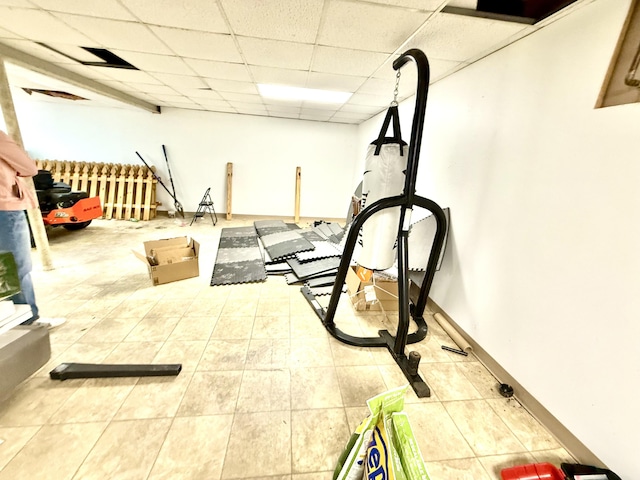 workout area featuring a paneled ceiling, baseboards, and tile patterned floors