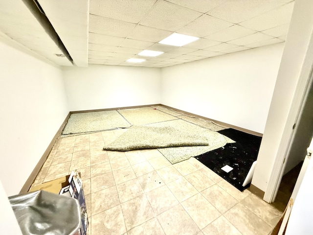 interior space featuring a drop ceiling, tile patterned flooring, and baseboards