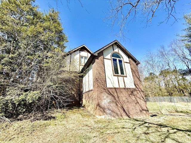 view of property exterior featuring brick siding, fence, and stucco siding