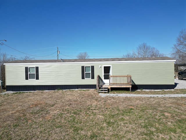 back of property featuring a wooden deck and a yard