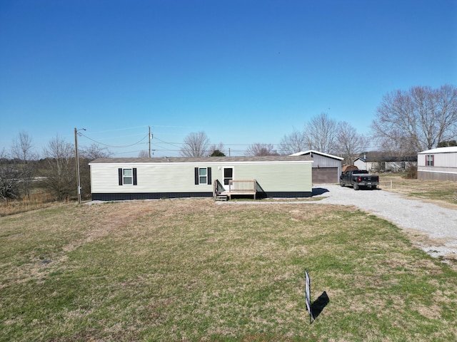 manufactured / mobile home featuring an outbuilding, a deck, and a front lawn