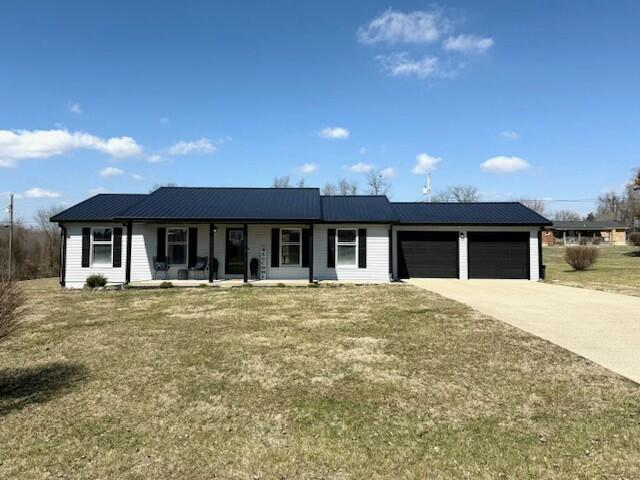 single story home with metal roof, concrete driveway, a porch, and an attached garage