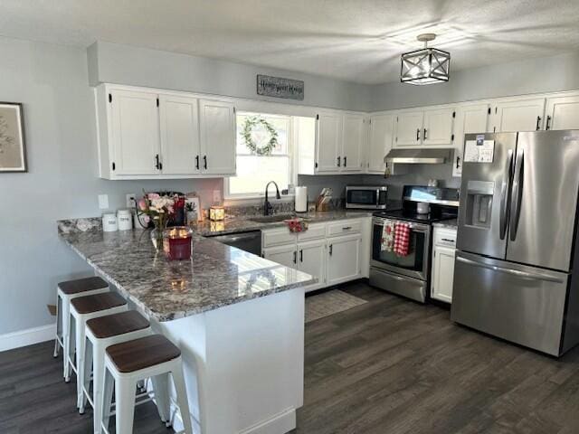 kitchen with under cabinet range hood, white cabinetry, stone counters, and stainless steel appliances