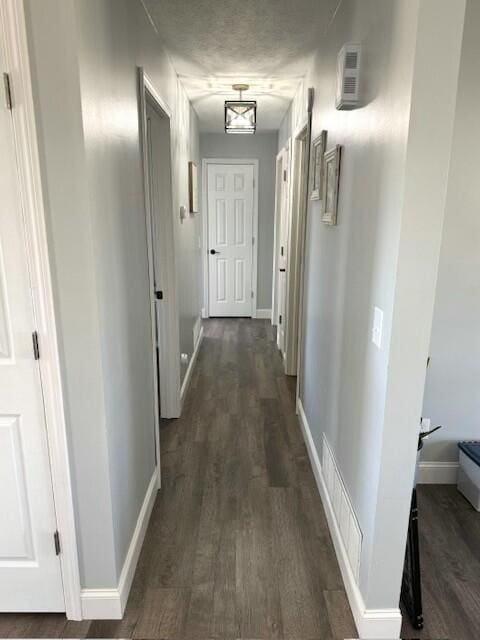 hallway featuring dark wood-style floors, visible vents, and baseboards