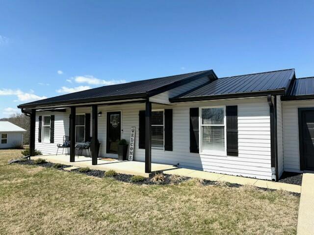 view of front of home featuring metal roof and a front lawn