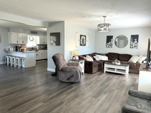 living room featuring baseboards, dark wood finished floors, and a chandelier