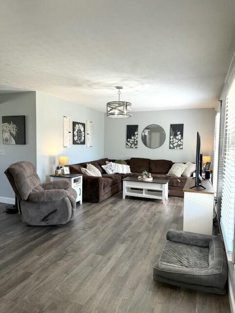 living area with baseboards, a chandelier, and wood finished floors