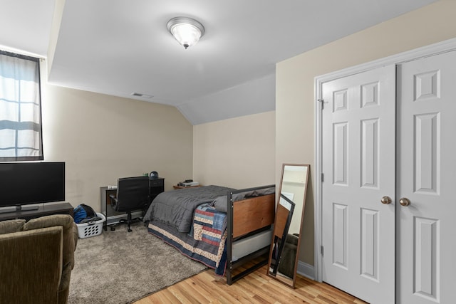 bedroom with lofted ceiling, light wood-style flooring, and visible vents