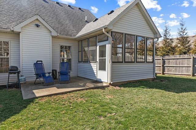 back of house featuring fence, a yard, roof with shingles, a sunroom, and a patio area