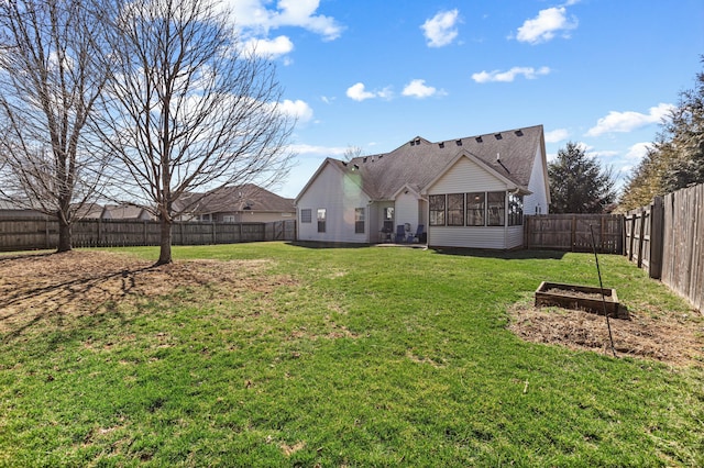 rear view of house with a shingled roof, a lawn, a fenced backyard, and a sunroom