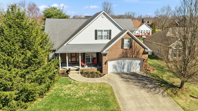 view of front of home featuring brick siding, a porch, a front yard, a garage, and driveway