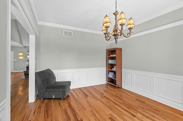 living area featuring visible vents, wood finished floors, crown molding, and a chandelier