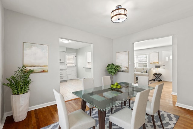 dining space featuring light wood-type flooring and baseboards