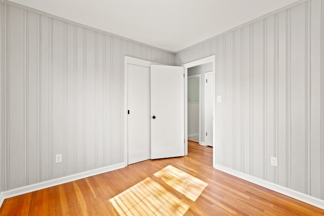 unfurnished bedroom featuring light wood-style flooring, baseboards, and a closet