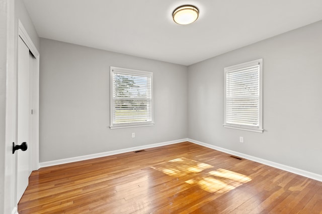 unfurnished bedroom featuring light wood-style flooring, visible vents, a closet, and baseboards