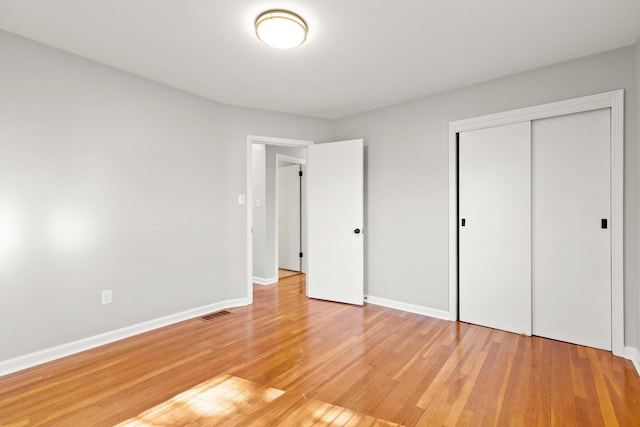 unfurnished bedroom featuring a closet, visible vents, light wood-type flooring, and baseboards