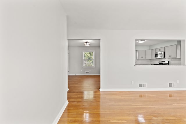 unfurnished living room featuring light wood-style floors, visible vents, and baseboards