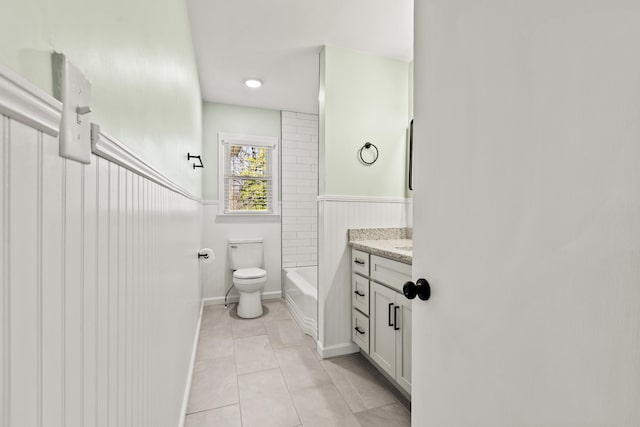 full bathroom with tile patterned floors, a wainscoted wall, toilet, and vanity