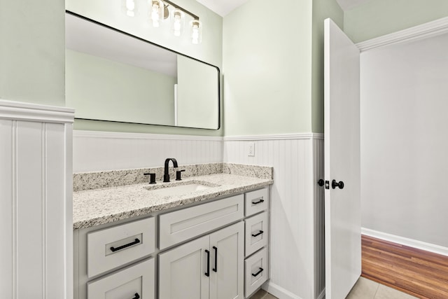 bathroom featuring a wainscoted wall, wood finished floors, and vanity