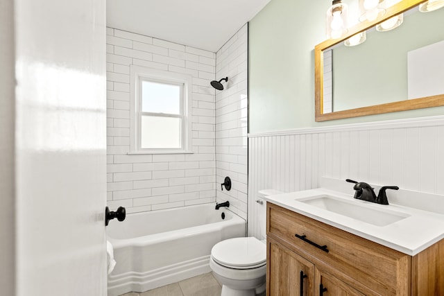 bathroom with tile patterned floors, a wainscoted wall, toilet, bathing tub / shower combination, and vanity