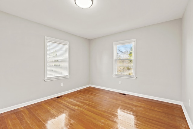 spare room with visible vents, baseboards, and hardwood / wood-style floors