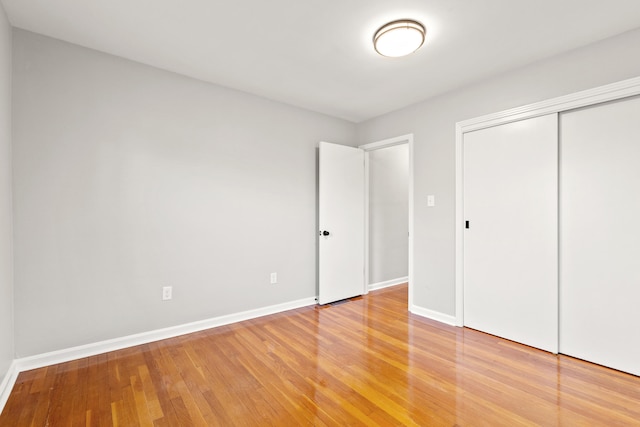 unfurnished bedroom featuring a closet, baseboards, and light wood finished floors