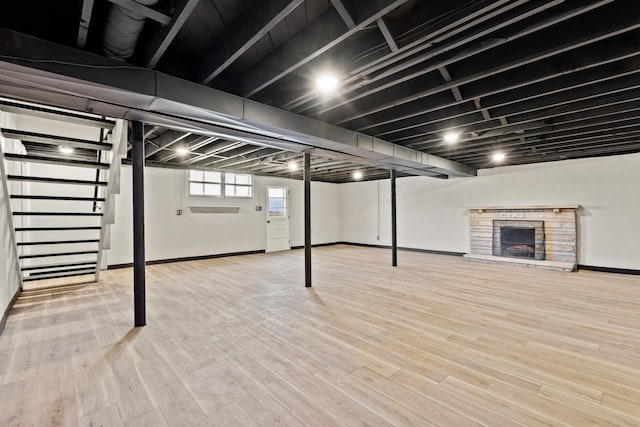 below grade area featuring wood finished floors, stairway, a fireplace, and baseboards