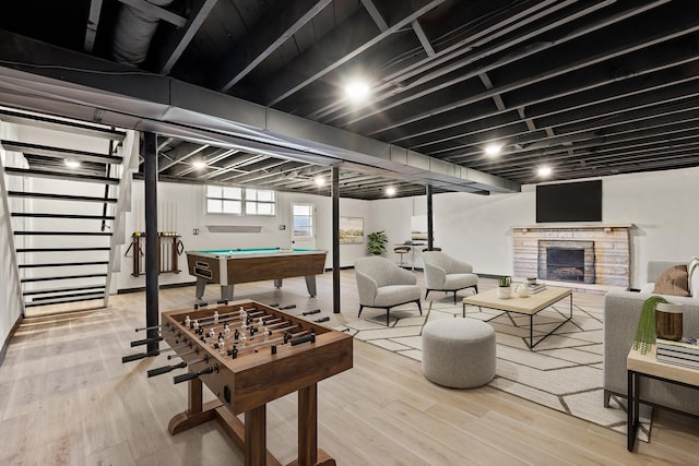 playroom with a stone fireplace, billiards, and wood finished floors