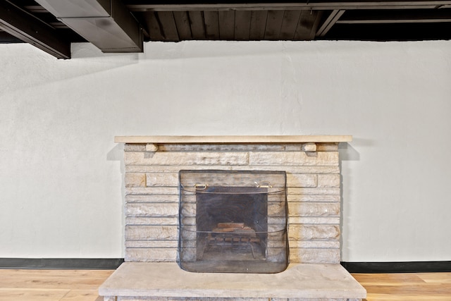 details featuring a stone fireplace, baseboards, and wood finished floors