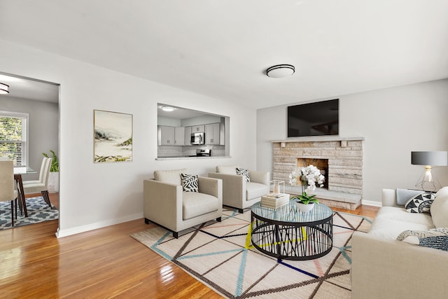 living area with baseboards, light wood-style flooring, and a fireplace