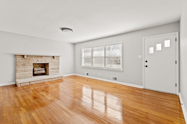 unfurnished living room featuring visible vents, light wood-style flooring, a fireplace, and baseboards