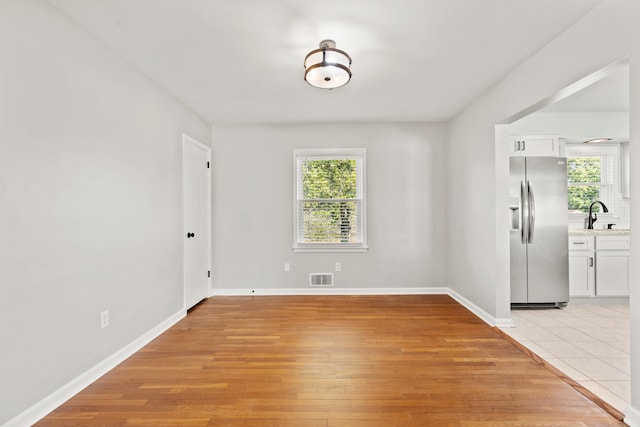 interior space with a sink, visible vents, plenty of natural light, and light wood-style flooring