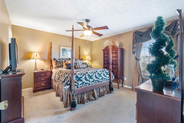 bedroom featuring light carpet, a ceiling fan, baseboards, and a textured ceiling