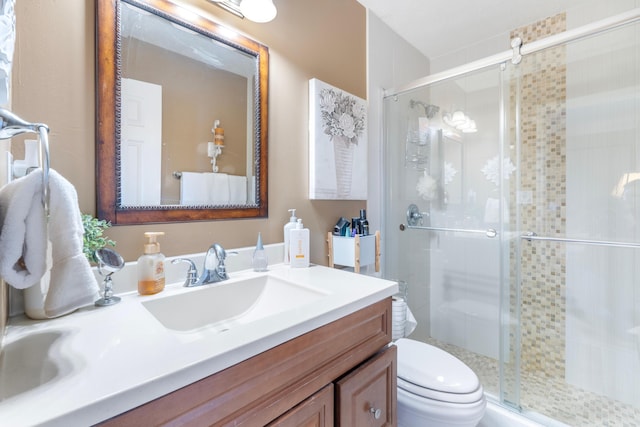 bathroom featuring a shower stall, toilet, and vanity