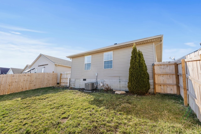 back of property with cooling unit, a fenced backyard, and a lawn